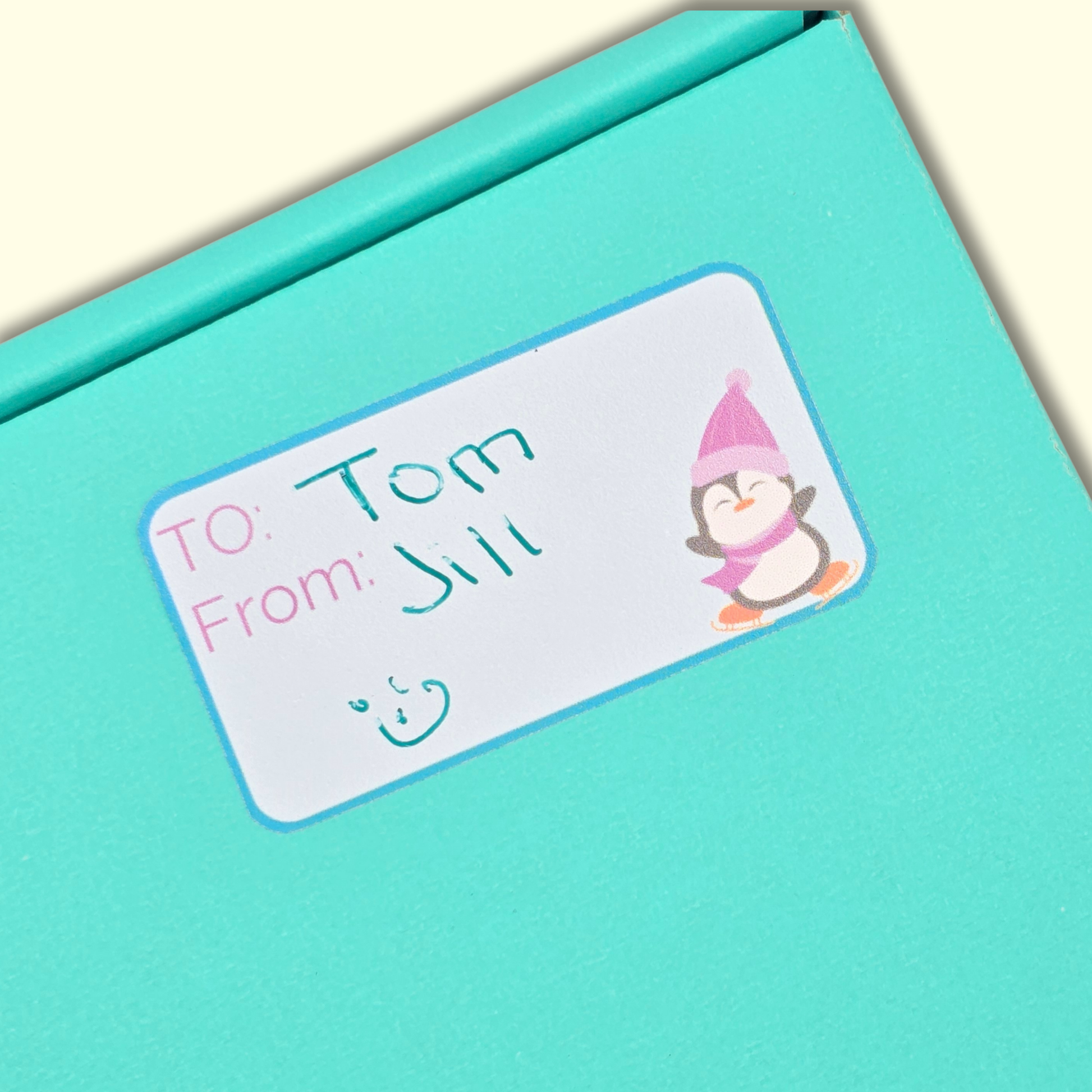 Turquoise gift box with a personalized label featuring a cartoon penguin.